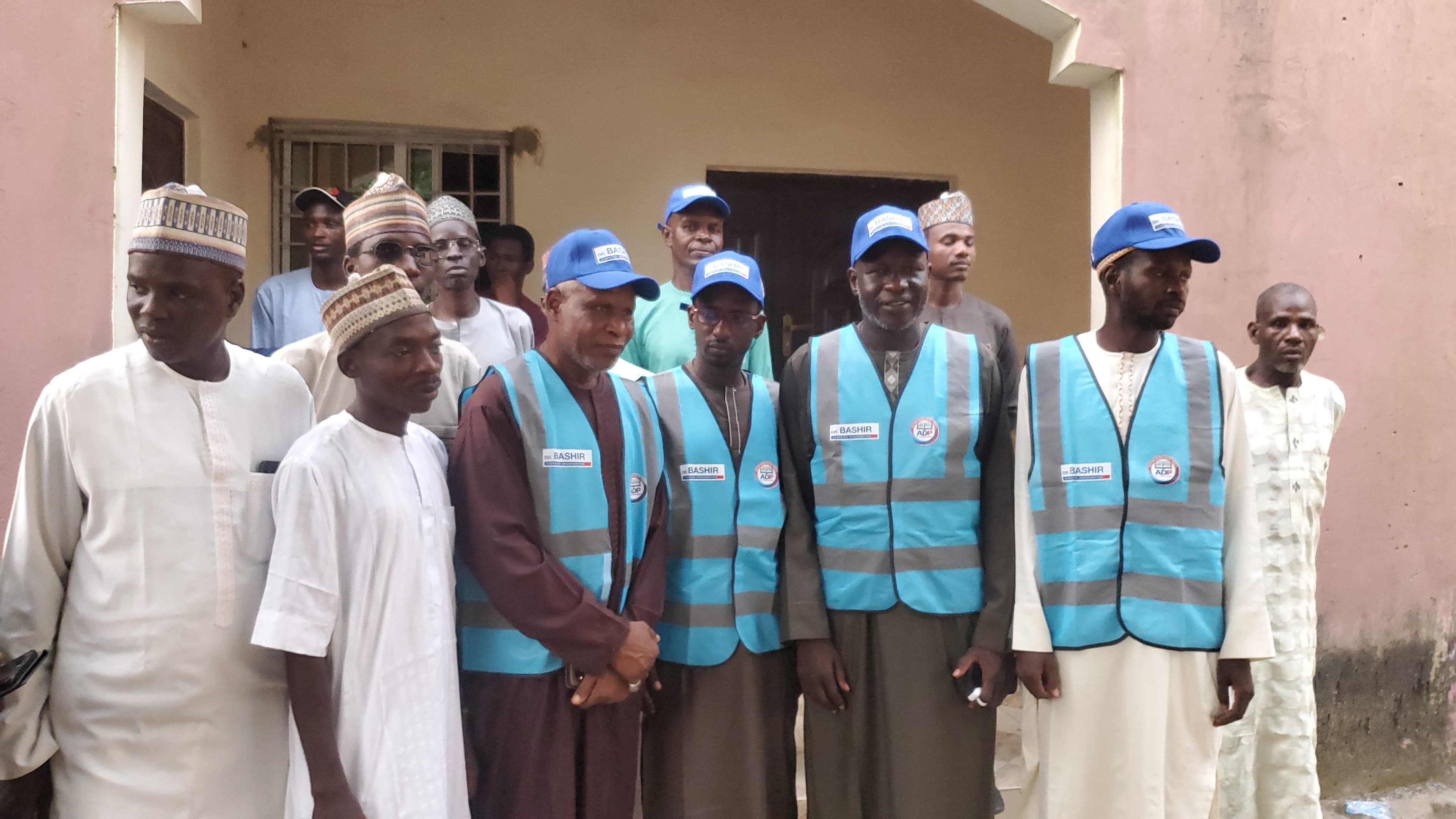 Programme team and community members gathered in Dorayi, wearing blue campaign vests and caps.